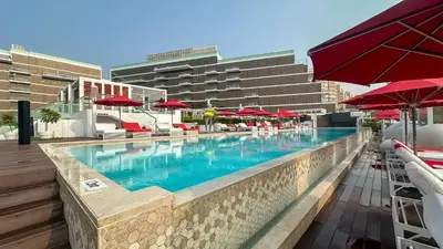 a large swimming pool with red umbrellas and chairs at Waves - Premium Seaside Retreat With Private Beach in Dubai