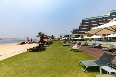 a row of lounge chairs on the beach next to a pool at Waves - Premium Seaside Retreat With Private Beach in Dubai