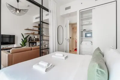 a bedroom with a white bed and a living room at Cozy 1BR Near Dubai Hills Park in Dubai
