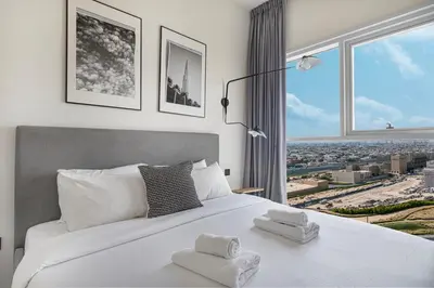 a bedroom with a large white bed with a large window at Cozy 1BR Near Dubai Hills Park in Dubai