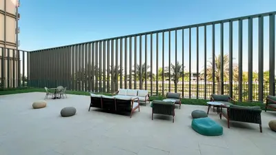 a patio with chairs and tables and a fence at Cozy 1BR Near Dubai Hills Park in Dubai