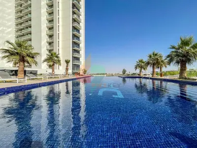 a large swimming pool with palm trees and a building at Damac Golf vita in Dubai