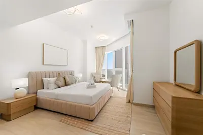 a white bedroom with a bed and a tv at Stylish 1 BR Apartment close to JBR Beach in Dubai