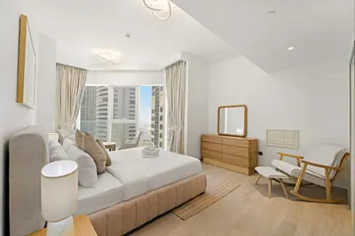 a white bedroom with a large bed and a window at Stylish 1 BR Apartment close to JBR Beach in Dubai