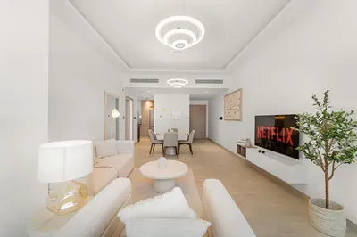 a white living room with a couch and a tv at Elegant 1 BR Apartment near Mall of the Emirates in Dubai