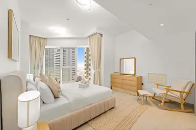 a white bedroom with a large bed and a window at Elegant 1 BR Apartment near Mall of the Emirates in Dubai