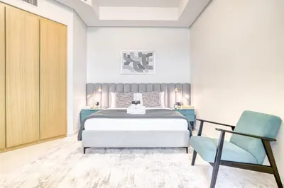 a bedroom with a bed and a blue chair at Cozy High-Floor Studio with Amazing Views in Dubai