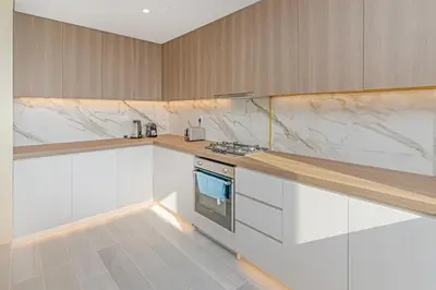a kitchen with white cabinets and marble counter tops at Savis Homes - Condor Marina Star - Luxury 2 BR Waterfront Apartment in Dubai
