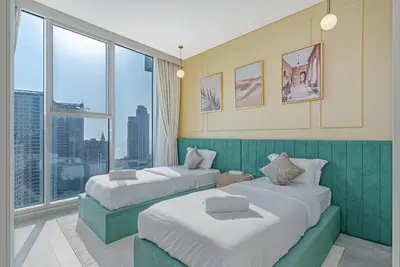 two beds in a room with a large window at Savis Homes - Condor Marina Star - Luxury 2 BR Waterfront Apartment in Dubai