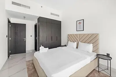 a bedroom with a large white bed and a stool at Amazing 1 Bdr luxury residence Dubai Arjan in Dubai