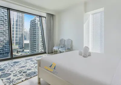 a bedroom with a large white bed and large windows at Luxurious 2 Bed Next to Burj Khalifa, Hosted by Desert City Stays in Dubai