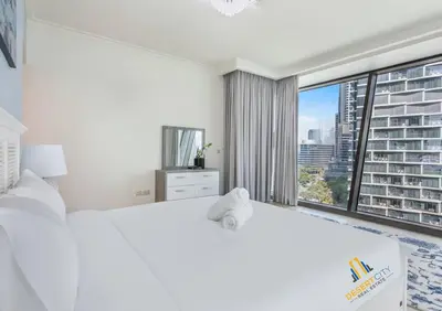 a bedroom with a white bed and a large window at Luxurious 2 Bed Next to Burj Khalifa, Hosted by Desert City Stays in Dubai