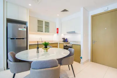 a kitchen with a table and chairs and a refrigerator at Creekside, Creek Harbour 1 BDR in Dubai
