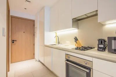 a kitchen with white cabinets and a stove at Marquise Square Studio, Business Bay in Dubai