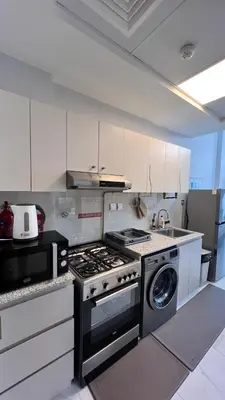 a kitchen with a stove and a washing machine at Millennium Binghatti Residence in Dubai
