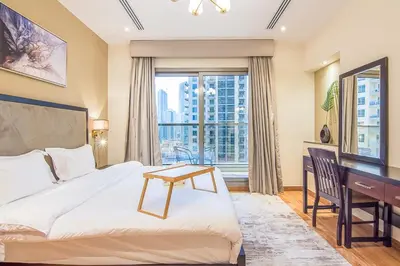a bedroom with a bed and a desk and a window at Elite 1 BR, Downtown in Dubai