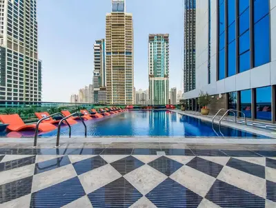a pool with red chairs and a city skyline at MBL Residences 1 BR, JLT in Dubai