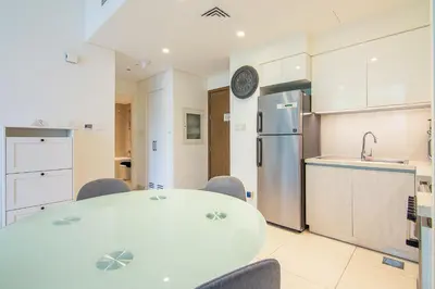 a kitchen with a table and chairs and a refrigerator at Park Point 1 BR, Dubai Hills in Dubai