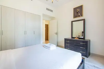 a bedroom with a large white bed and a mirror at Park Point 1 BR, Dubai Hills in Dubai