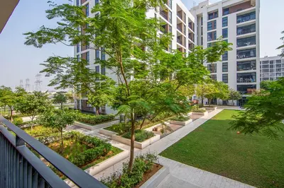 a garden with trees and grass in front of a building at Park Point 1 BR, Dubai Hills in Dubai