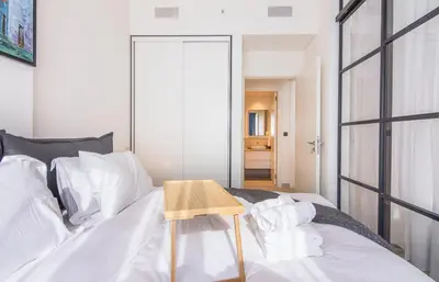 a bedroom with a white bed with a wooden table on it at Collective 1,0 Dubai Hills- Cozy 1-BR in Dubai