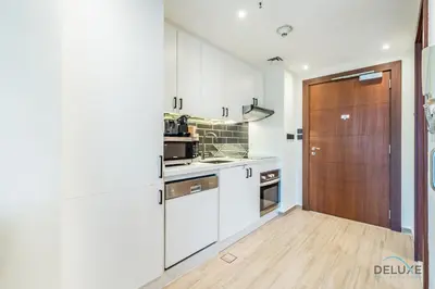 a kitchen with white cabinets and a wooden door at Exclusive Promo Luxe 1BR at a Special Price by Deluxe Holiday Homes in Dubai