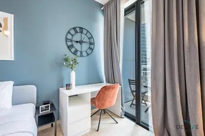 a bedroom with a bed and a desk and a clock at Exclusive Promo Luxe 1BR at a Special Price by Deluxe Holiday Homes in Dubai