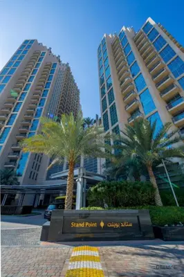 a sign in front of a large building with palm trees at Exclusive Promo Luxe 1BR at a Special Price by Deluxe Holiday Homes in Dubai