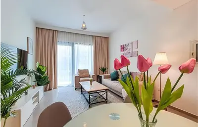 a living room with a couch and a table with pink flowers at Park Heights, Dubai Hills- Cozy 1-BR in Dubai