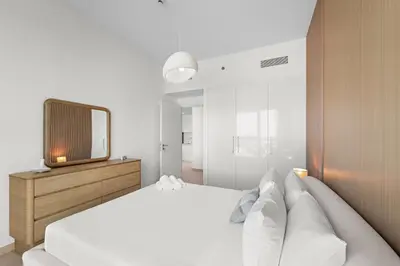 a white bedroom with a bed and a tv at Chic 1BR Retreat - Near Burj Khalifa & Dubai Mall in Dubai