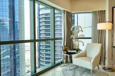 a living room with a chair and large windows at Luxurious 2BDR Apartment in Paramount Towers with Burj Khalifa Views in Dubai