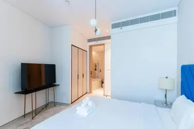a white bedroom with a bed and a flat screen tv at Address JBR l Beachfront l Mid floor & opened view in Dubai
