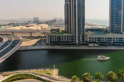 a river with a boat in a city with tall buildings at Address JBR l Beachfront l Mid floor & opened view in Dubai