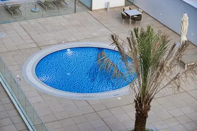 an overhead view of a swimming pool with a palm tree at Elegant Studio with Terrace 7 min Burj Khalifa in Dubai