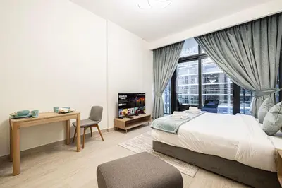 a bedroom with a bed and a desk and a window at Elegant Studio with Terrace 7 min Burj Khalifa in Dubai