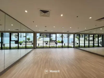 a large empty room with a wooden floor and windows at Manzil - Studio Apartment in Azizi Riviera near Dubai Mall in Dubai