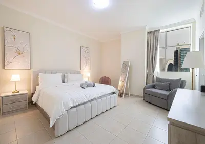 a white bedroom with a bed and a chair at lux 2BD in heart of Downtown, 2 Mins Walk to Dubai Mall - Burj al Nujoom in Dubai
