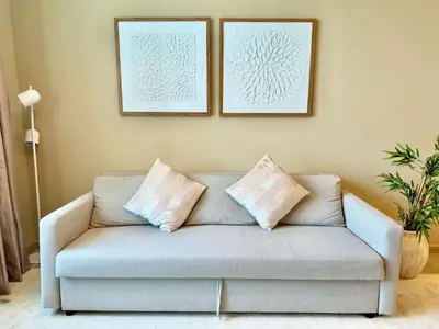 a couch in a living room with two pictures on the wall at Urban Oasis Stylish JLT Apartment with Lake Views in Dubai