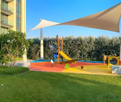 a park with a playground with skis and an umbrella at Charming 1BR Apartment in Downtown Views 1, Downtown Dubai by Deluxe Holiday Homes in Dubai