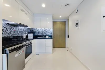 a kitchen with white cabinets and a door to a hallway at ALiving Charming 1BR I Aykon City Tower, Business Bay in Dubai