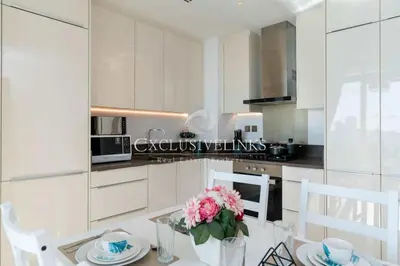 a kitchen with white cabinets and a table with pink flowers at Stunning 1Bed High Floor Marina View in Dubai