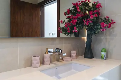 a bathroom with a sink with a vase of pink flowers at Stunning 1Bed High Floor Marina View in Dubai