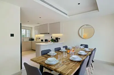 a dining room with a wooden table and chairs at Backyard Bliss Villa in The Lakes 3BR plus maid's room in Dubai