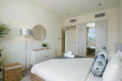 a white bedroom with a bed and a mirror at Backyard Bliss Villa in The Lakes 3BR plus maid's room in Dubai