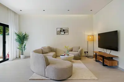 a living room with two chairs and a flat screen tv at Backyard Bliss Villa in The Lakes 3BR plus maid's room in Dubai