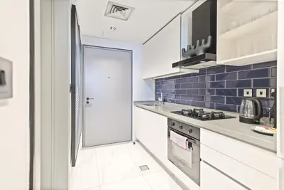 a kitchen with white cabinets and blue tiles at MAG318 Downtown Luxury - 5 Min Walk to Burj & Mall in Dubai