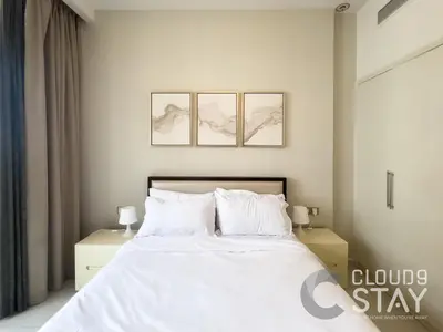a bedroom with a white bed with three pictures on the wall at Cloud 9 - DAMAC Ghalia Tower in Dubai