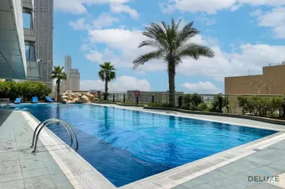 a large swimming pool with a palm tree and a building at Charming 1BR Apartment at Ocean Heights Dubai Marina by Deluxe Holiday Homes in Dubai