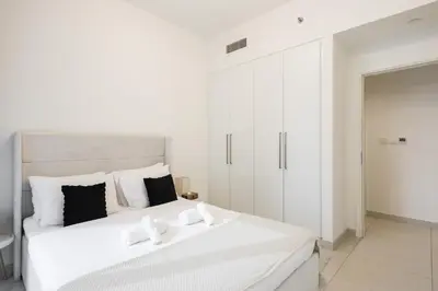 a white bedroom with a large bed and a cabinet at Downtown Apartments - Burj Crown - 5 Min Walk to Mall in Dubai