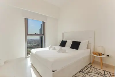 a white bedroom with a large white bed and a window at Sea & City Views - Burj Crown - 5 Min Walk to Mall in Dubai
